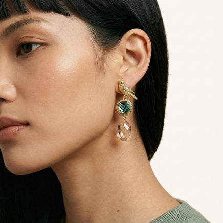 Close-up of model wearing gold songbird earring with round abalone shell and champagne crystal drop | Olaty