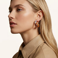 Model wearing twisted statement hoop earring with red and blue textured enamel finish | Olaty