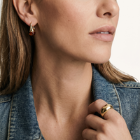 Close-up of model wearing sculptural amber resin drop earring with polished gold finish | Olaty