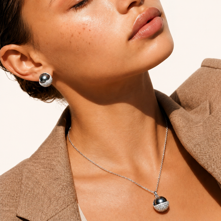 Close-up of dark sphere stud earring and matching zirconia pendant necklace | Olaty
